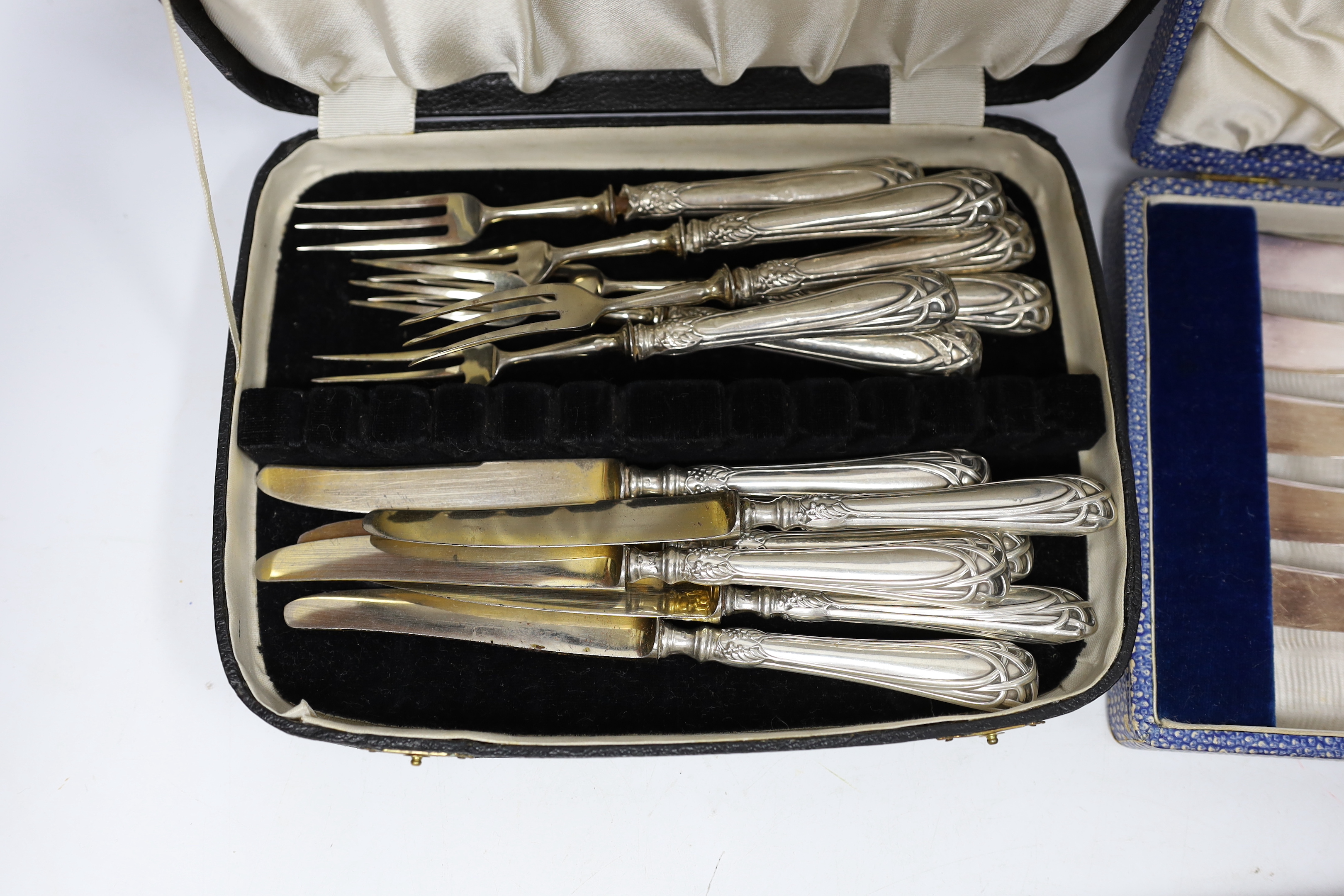 Six pairs of German Art Nouveau 800 standard white metal handled dessert eaters and two cased sets of six silver handled tea knives(one knife missing).